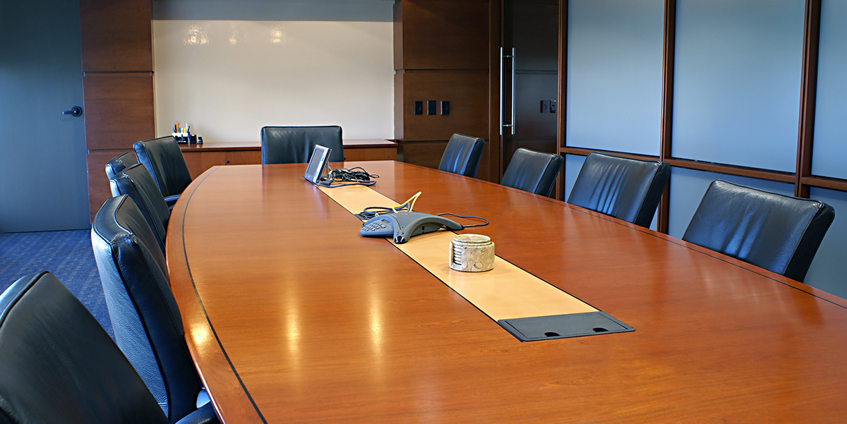 Board or conference room with expensive leather chairs and am oval=shaped wooden conference table.