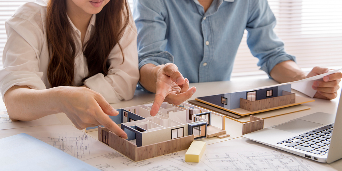 Woman and man in discussion pointing at building models discussing assets